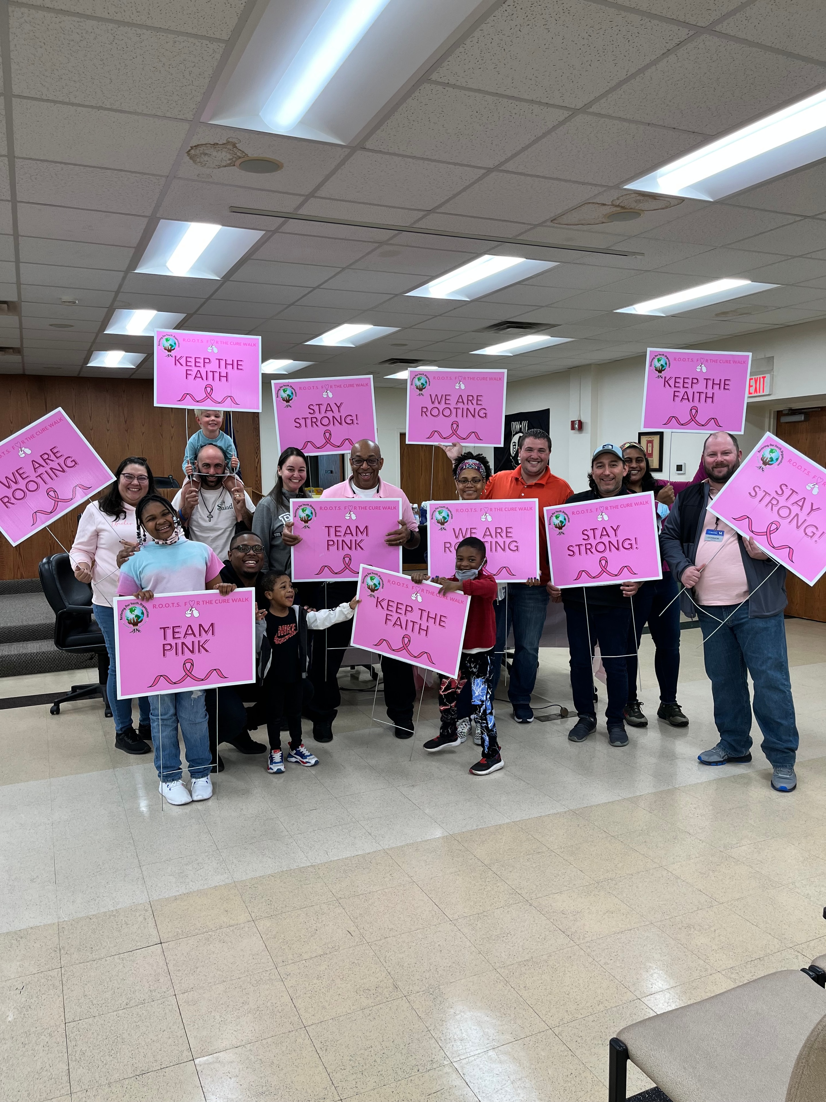 R.O.O.T.S team holding pink awareness signs